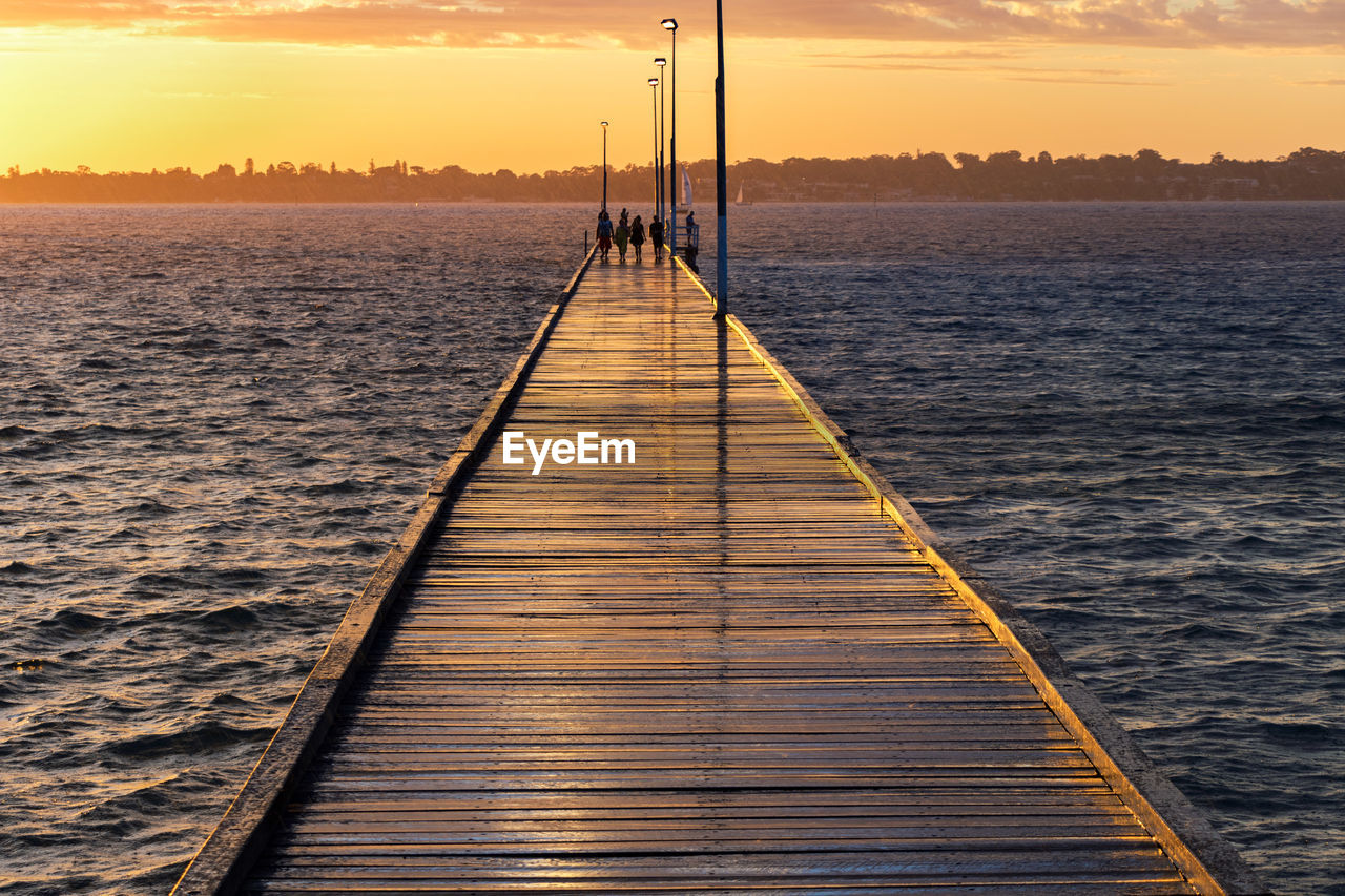 Pier over sea against sky during sunset