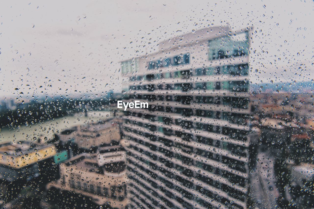 Buildings seen through wet glass window during rainy season