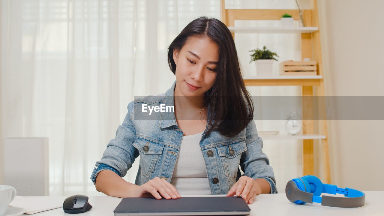 Young woman holding digital tablet on table at home