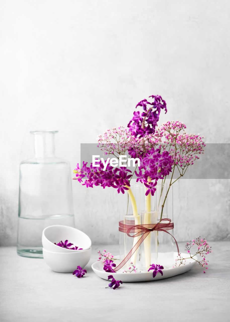 Still life with flower bouquet of fresh purple hyacinth, and pink gypsophila flowers in a glass vase