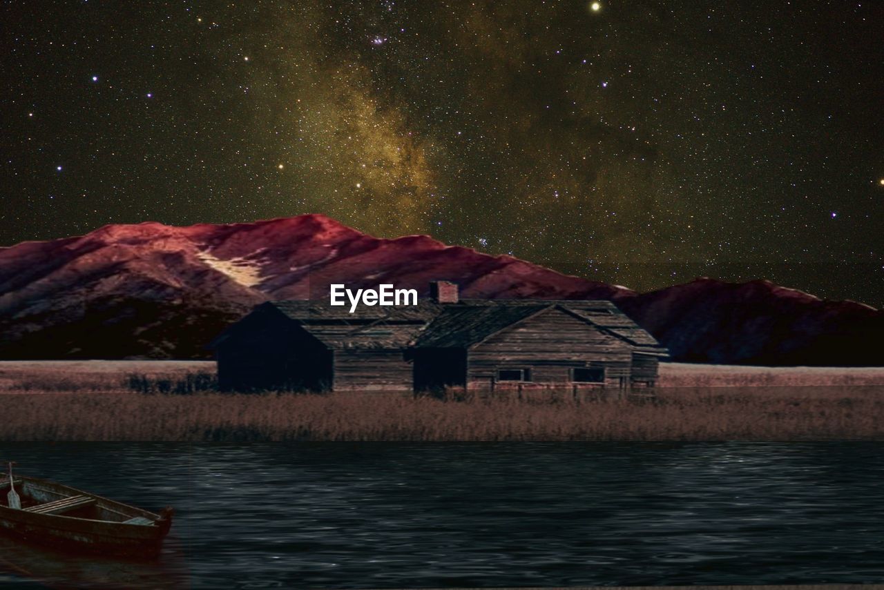 HOUSES BY LAKE AGAINST SKY AT NIGHT