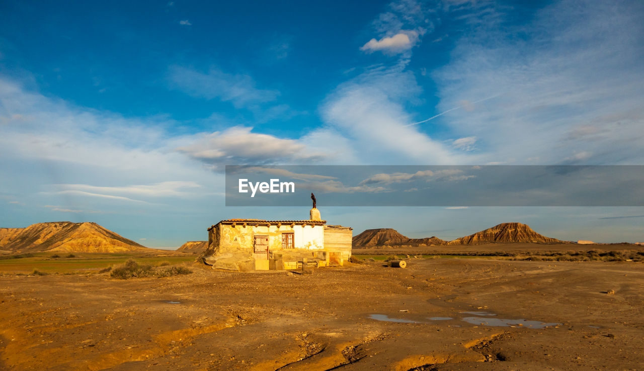 View of old building on land against cloudy sky