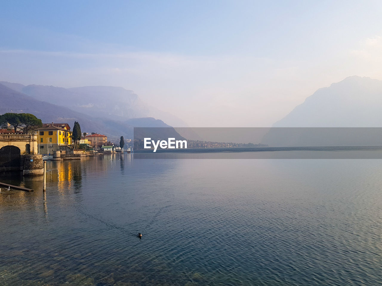 Mist at sunset over the blue lake como and mountains, lombardy italy 