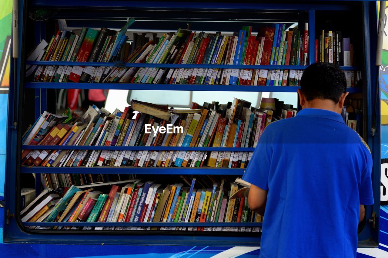 Rear view of man reading book at library