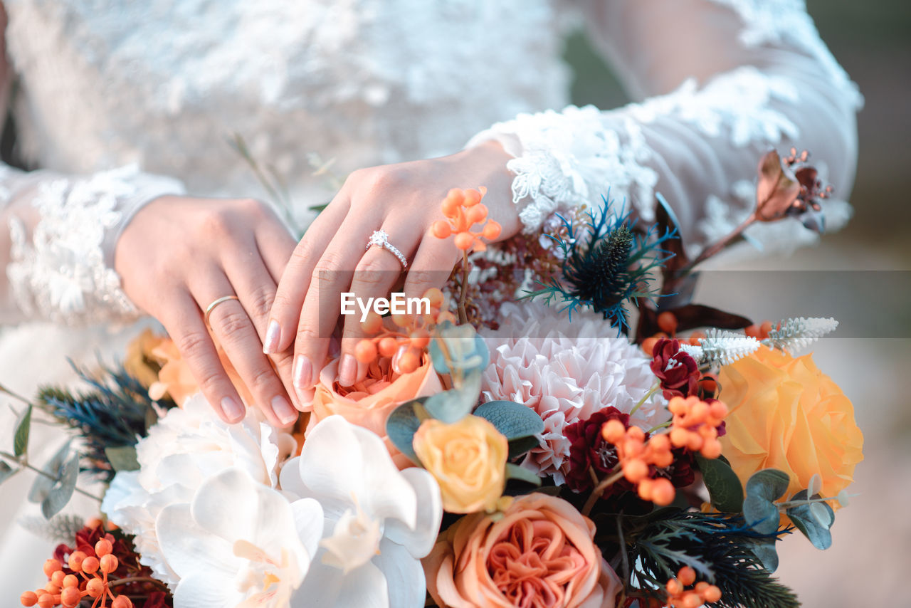 Midsection of woman holding flower bouquet outdoors