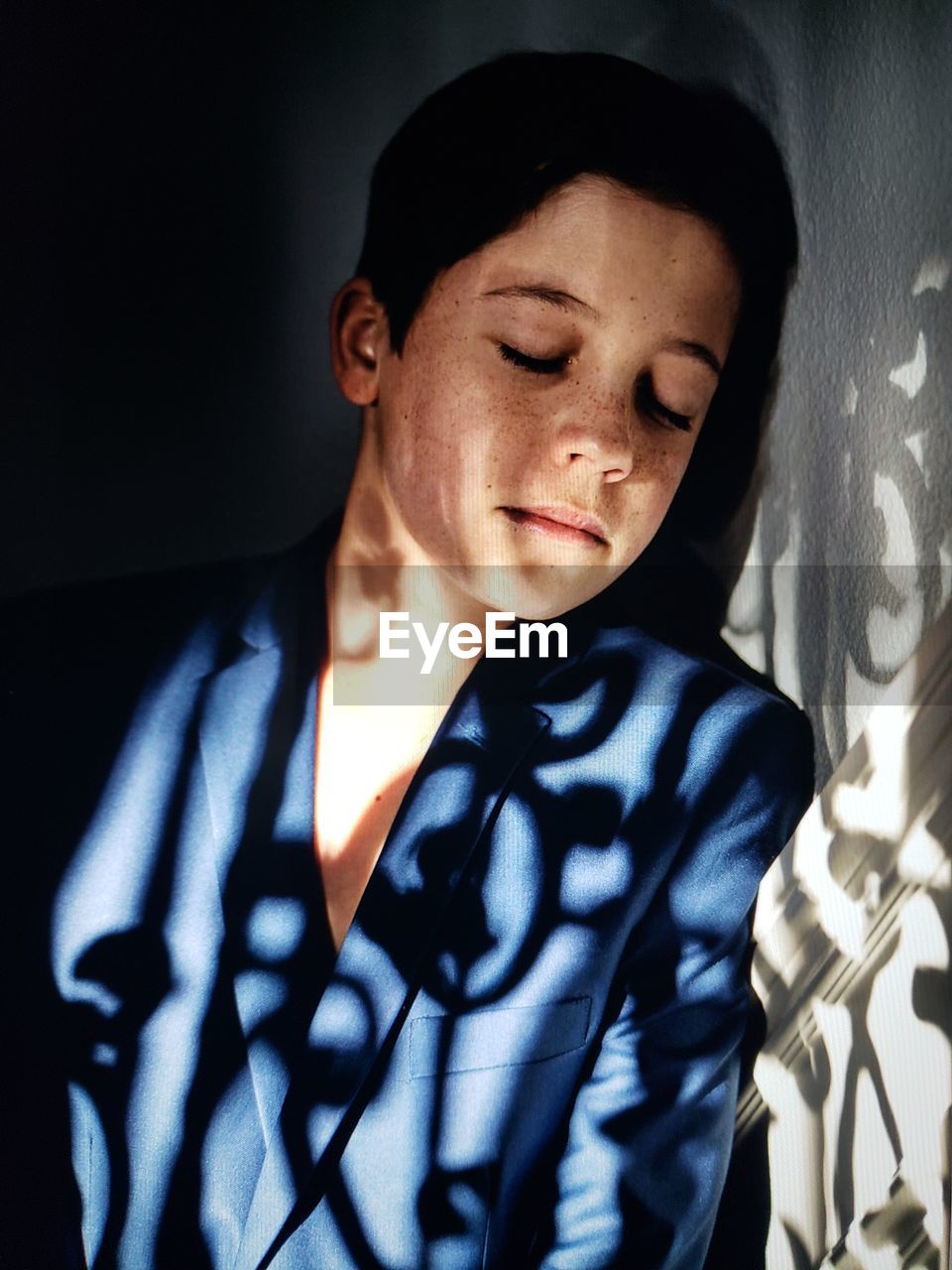 Close-up of girl with closed eyes standing against wall at home