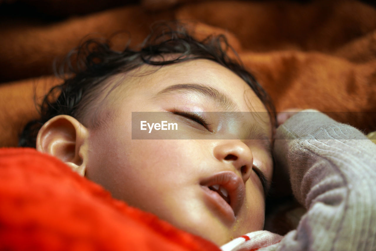 close-up of cute baby girl lying on bed at home