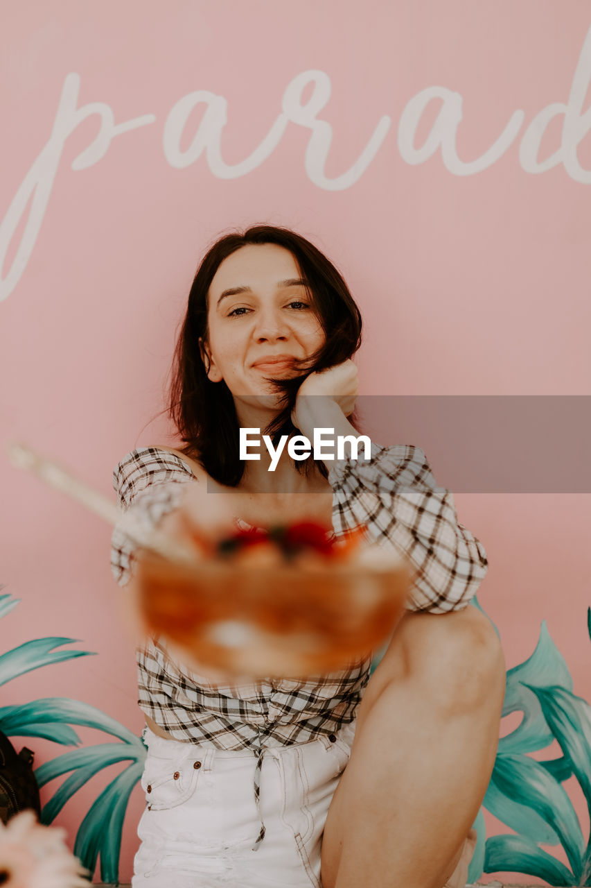 Portrait of smiling woman sitting by wall