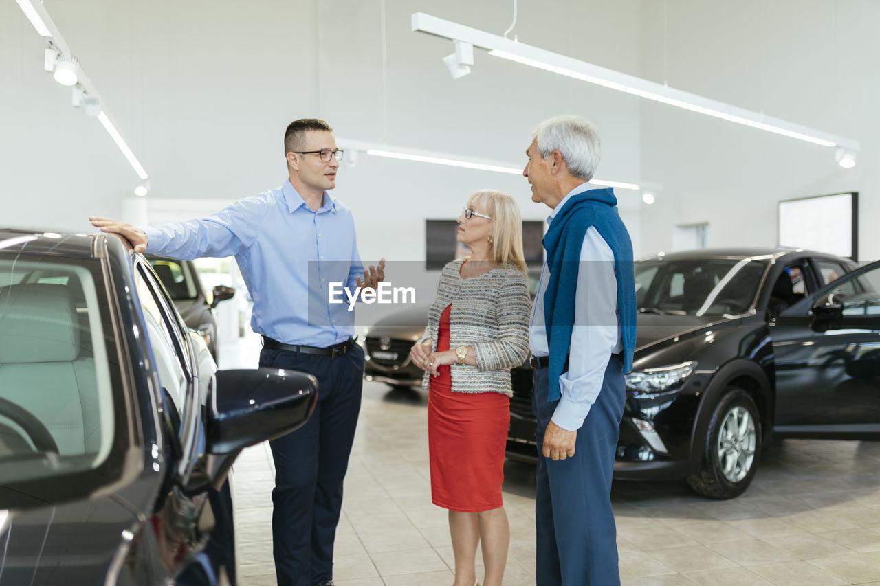 Senior couple couple talking with salesperson in car dealership