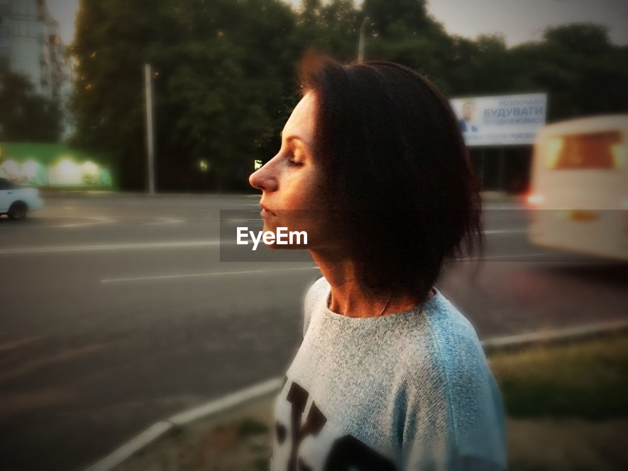 PORTRAIT OF YOUNG WOMAN LOOKING AWAY WHILE STANDING ON ROAD