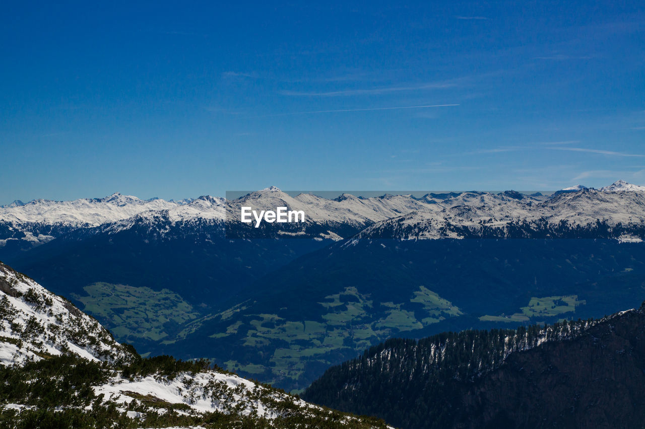 Scenic view of snowcapped mountains against blue sky