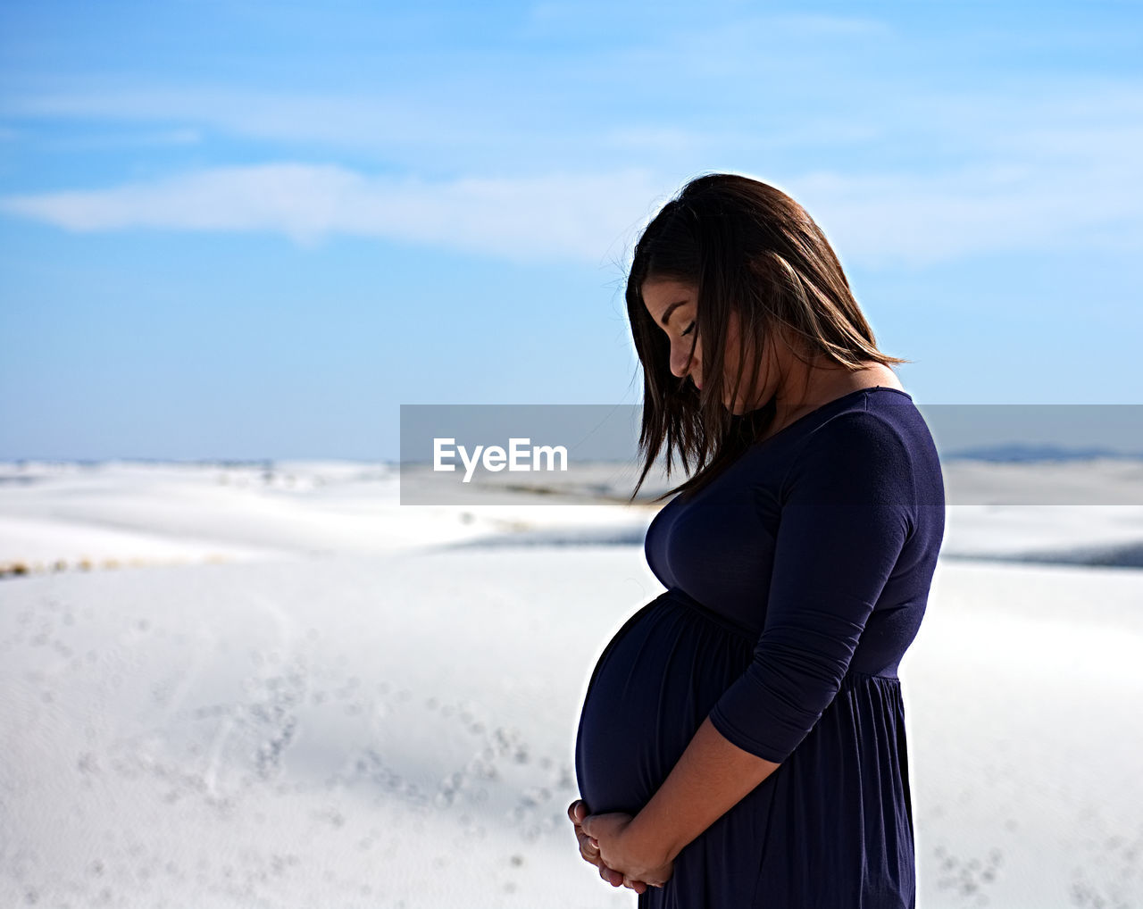 Side view of pregnant woman standing at beach against sky