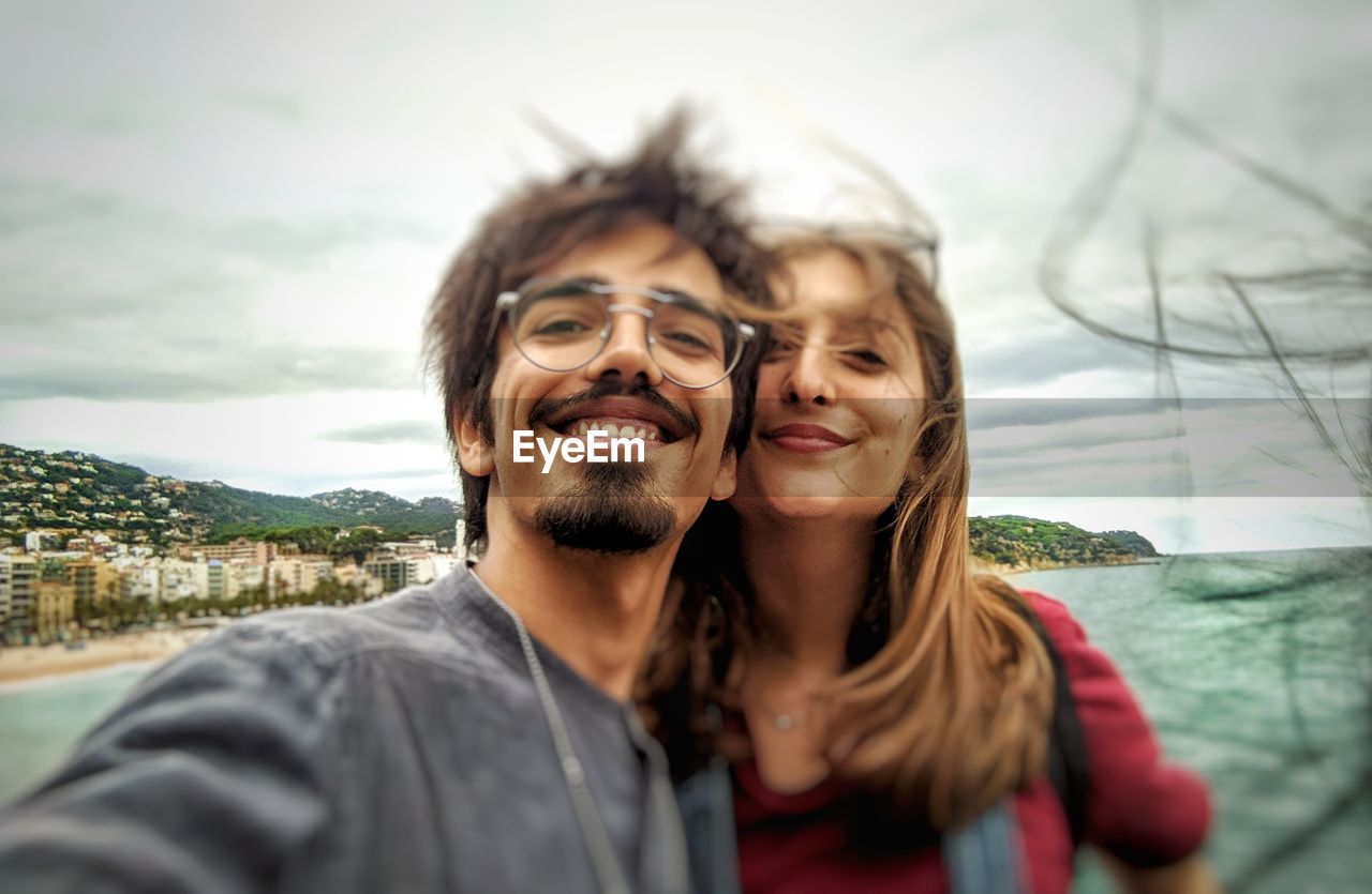 Portrait of smiling young couple standing against sea
