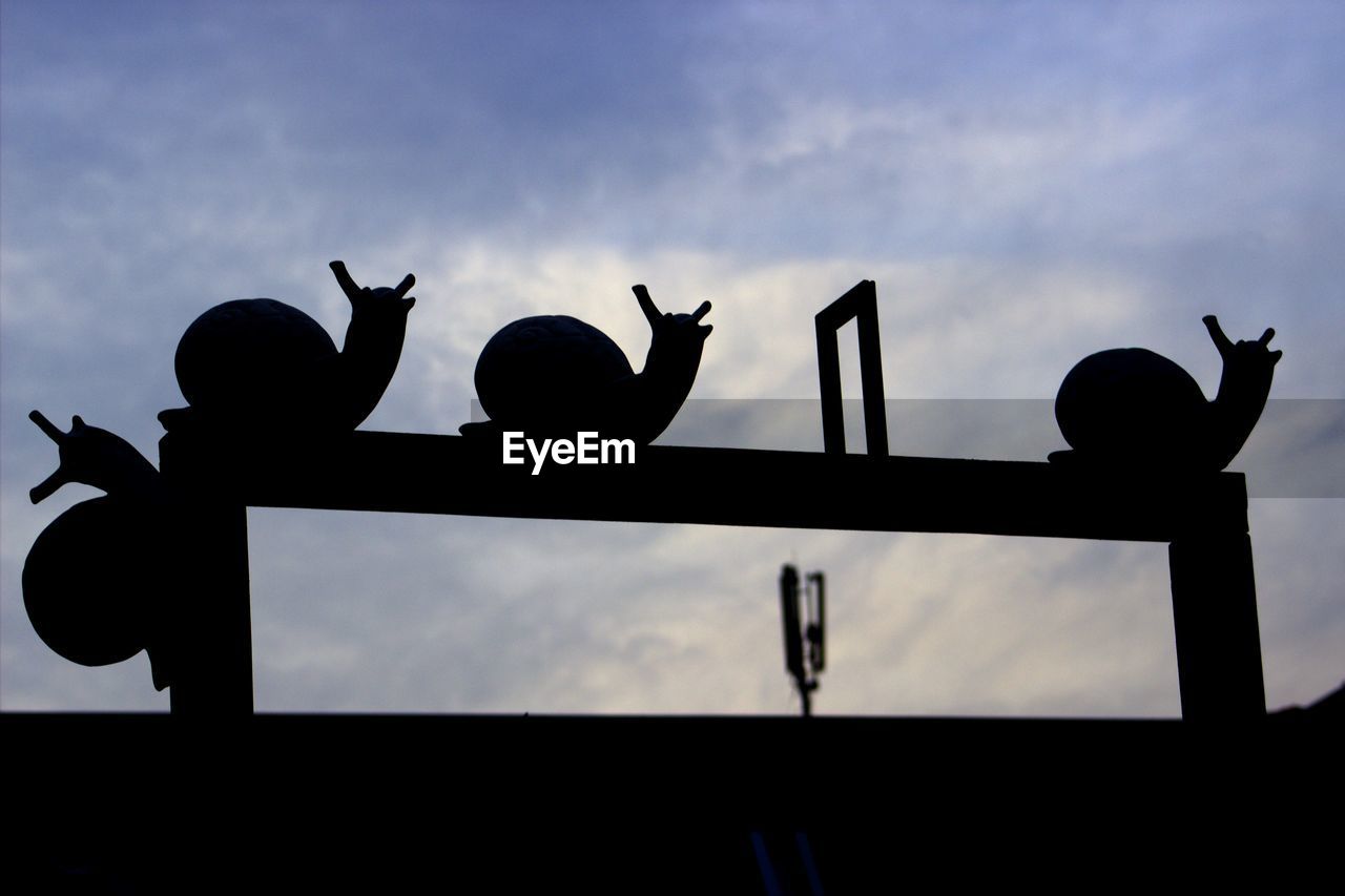 Low angle view of snail statues against cloudy sky