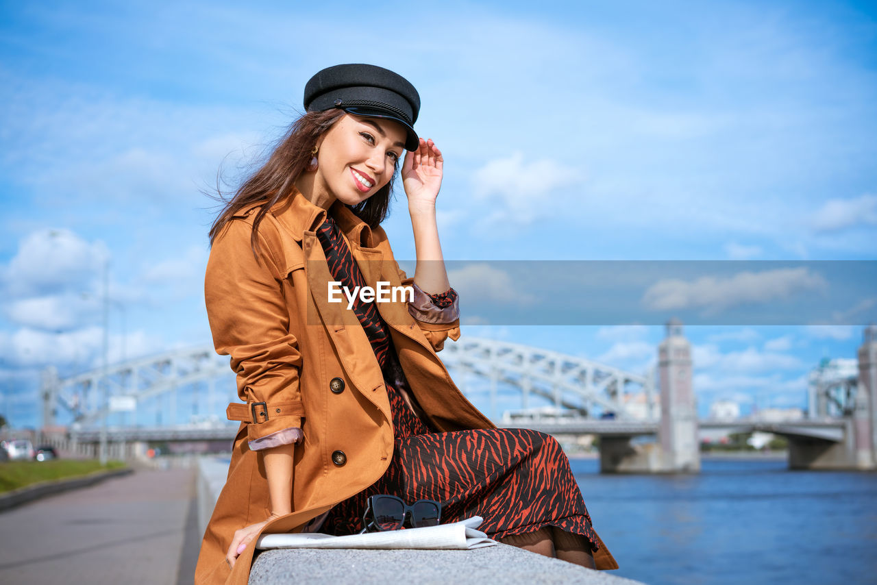 Portrait of a happy woman on the embankment of the river in a cap