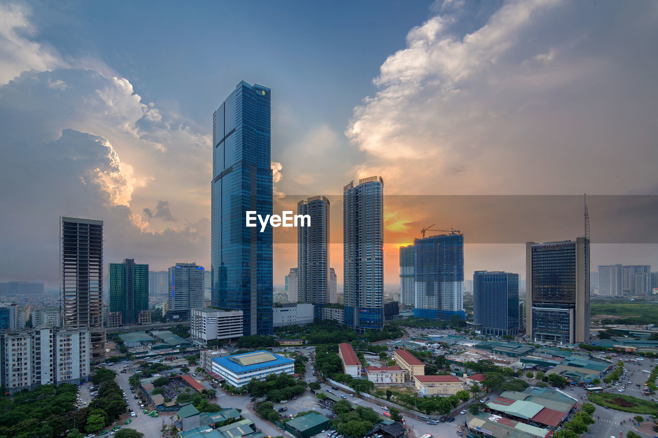 Modern buildings in city against sky during sunset