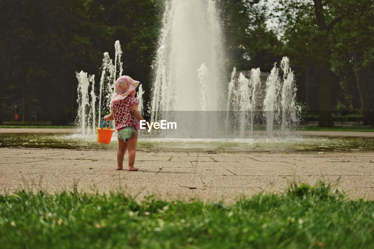 FULL LENGTH OF CHILD PLAYING WITH WATER IN PARK