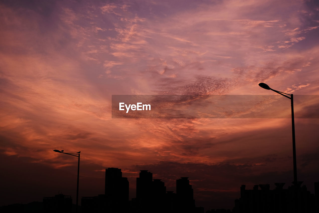 LOW ANGLE VIEW OF SILHOUETTE BUILDINGS AGAINST ORANGE SKY