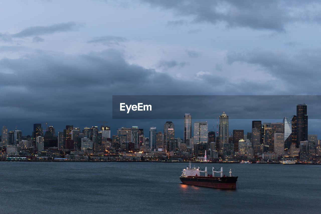 Sea and buildings in city against sky