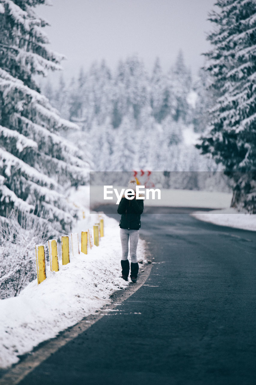 Woman photographing on road during winter