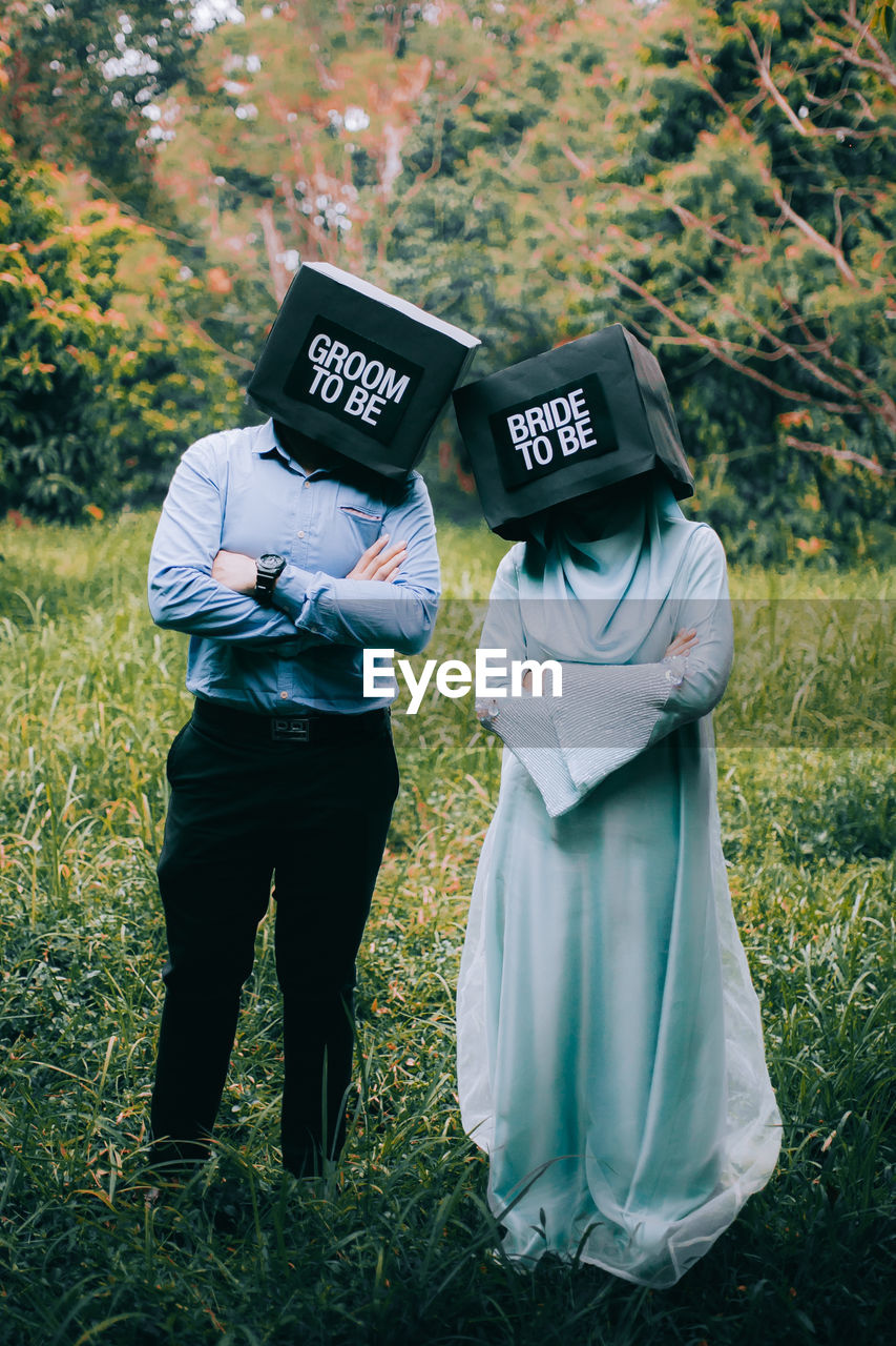 Couple wearing boxes with text while standing on field