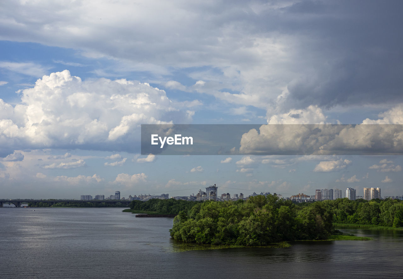 SCENIC VIEW OF RIVER BY BUILDINGS IN CITY AGAINST SKY