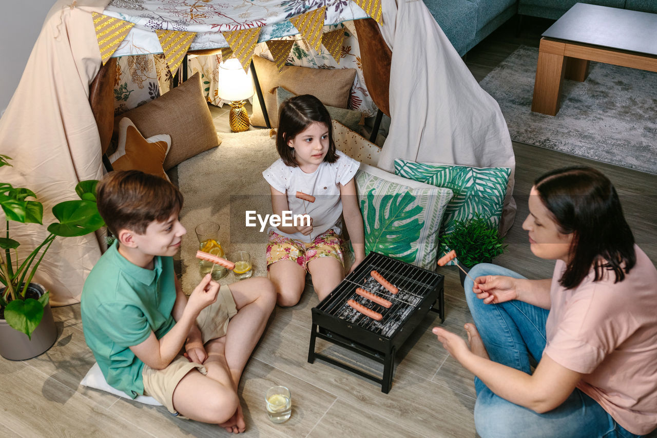 High angle view of mother with children eating barbecue meal at home