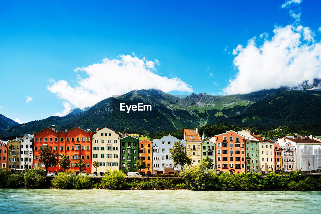 Buildings by lake against blue sky