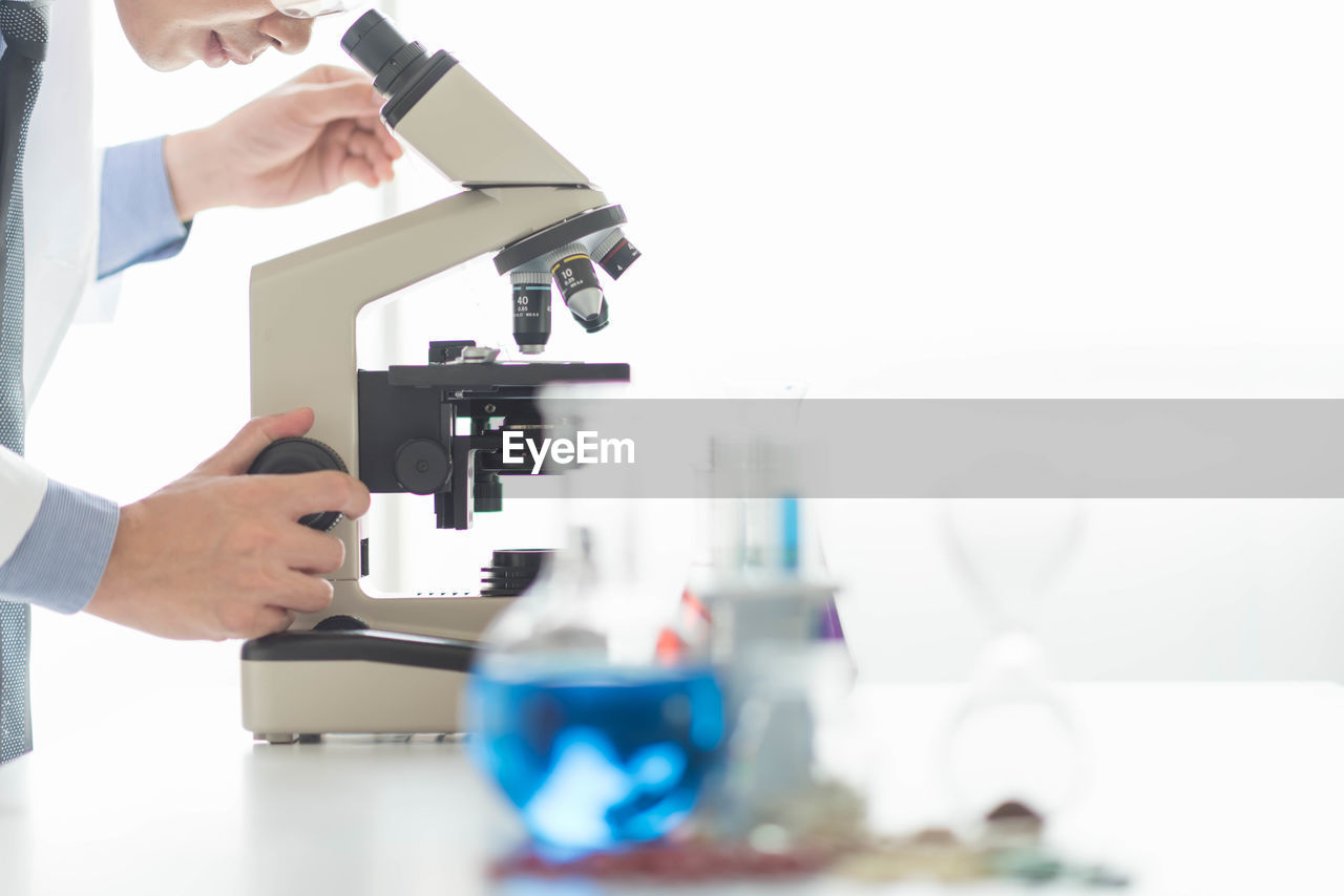 Midsection of man using microscope in lab