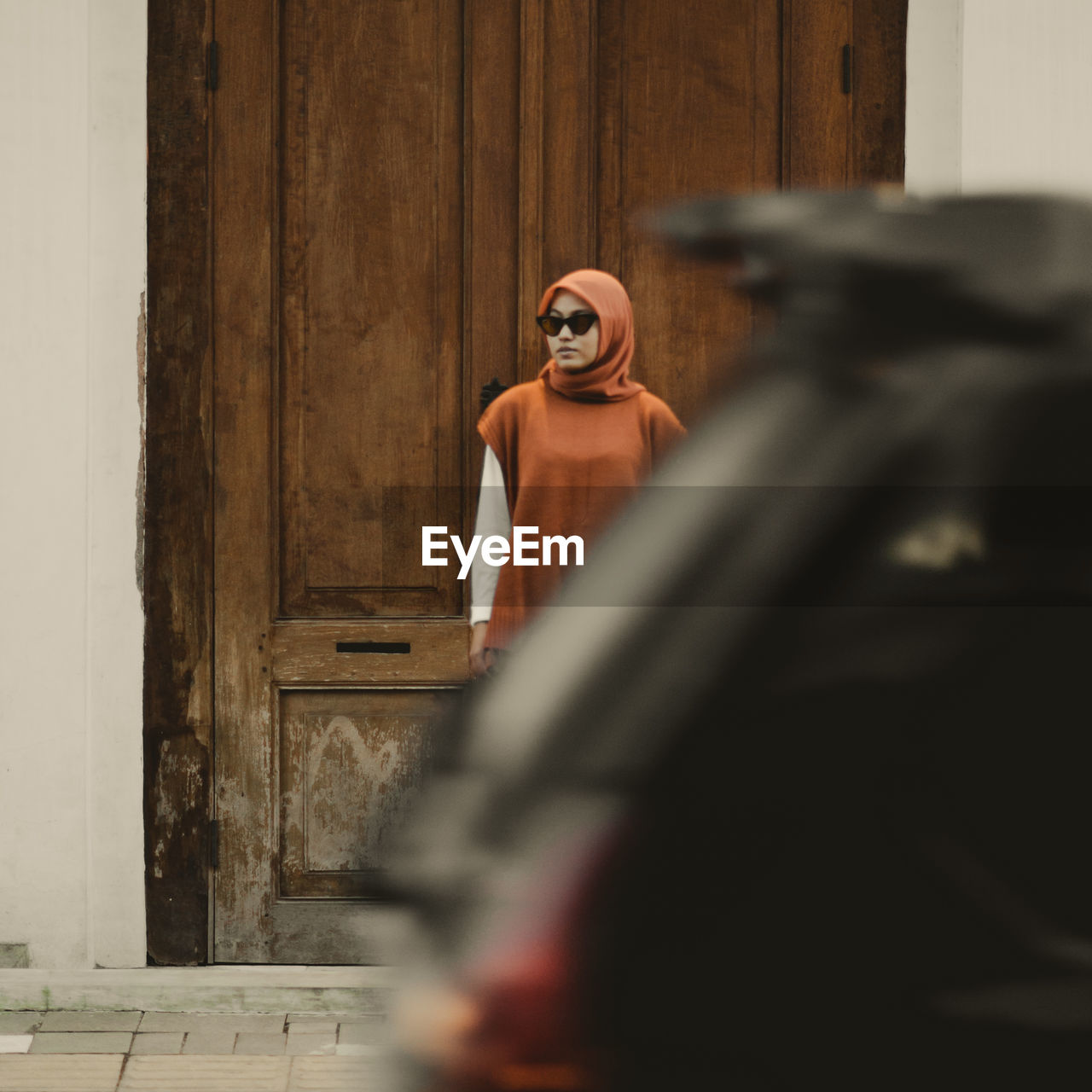 Woman standing near old wooden door