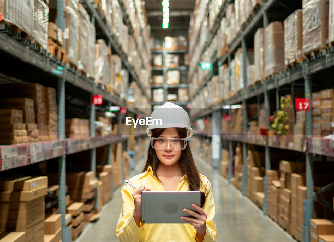 Female warehouse worker inspecting a warehouse in a factory. 