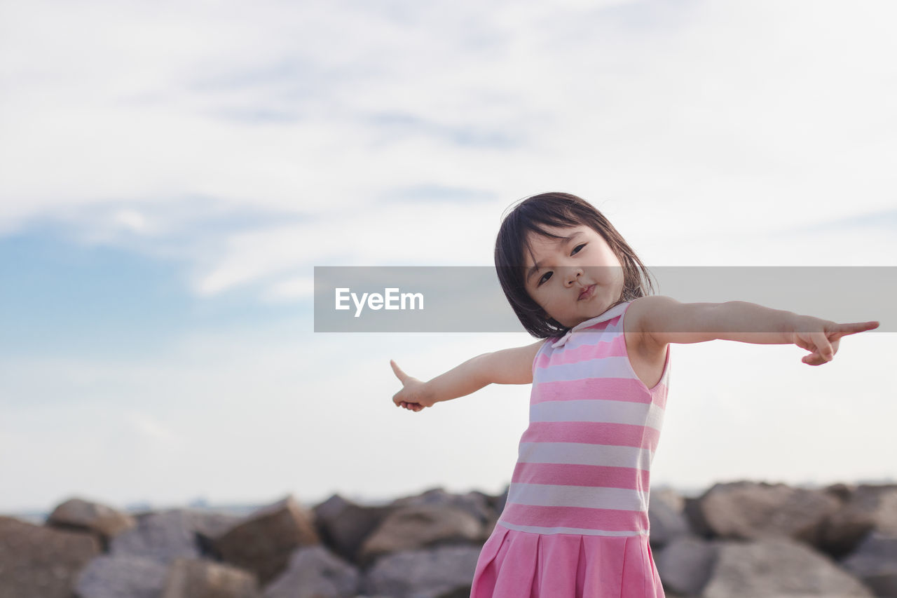 Girl standing on rock against sky