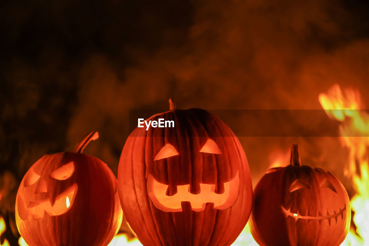 Illuminated jack o lanterns with fire in background at night