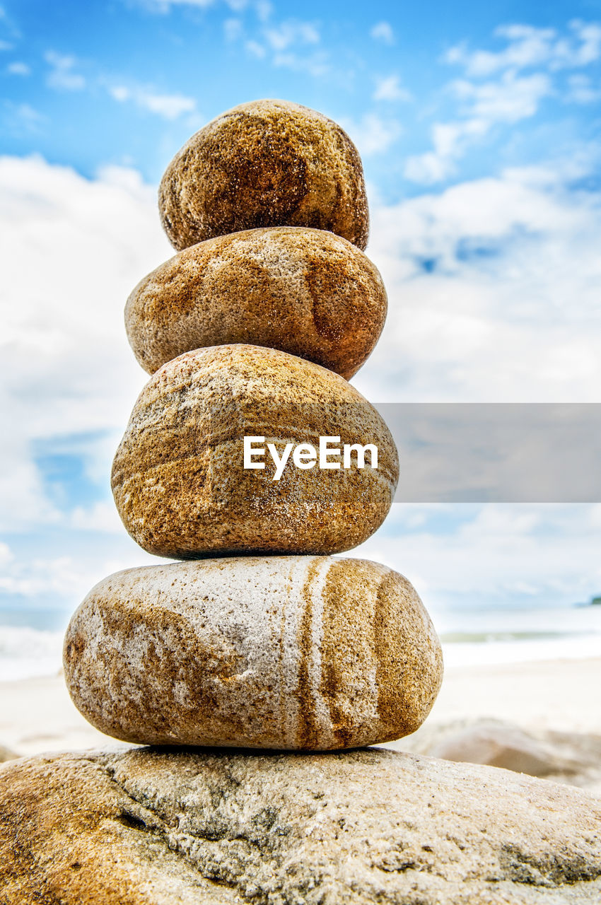 Close-up of stone stack on rock against sky 