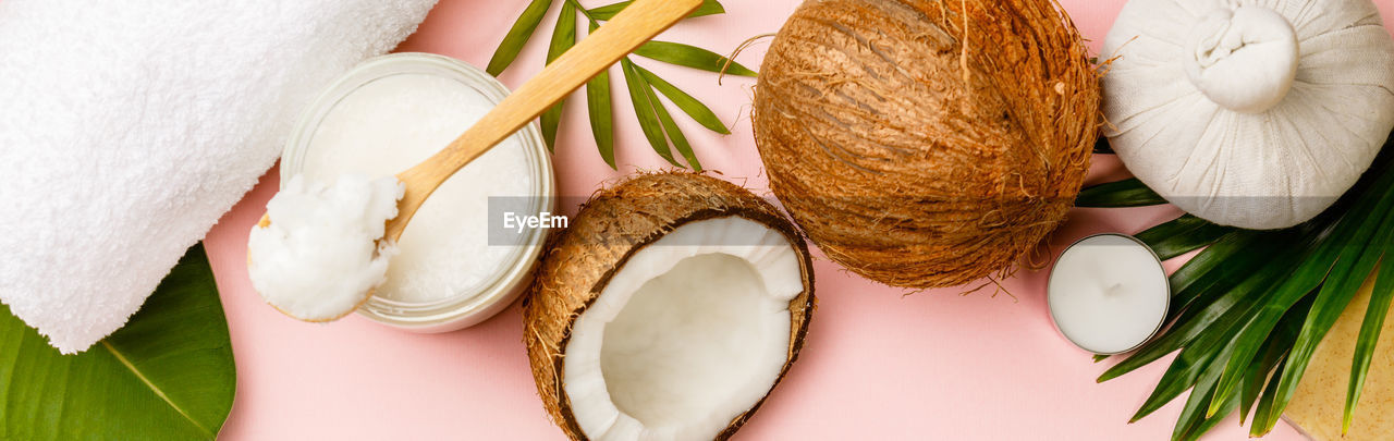 High angle view of coconut with leaves on pink background