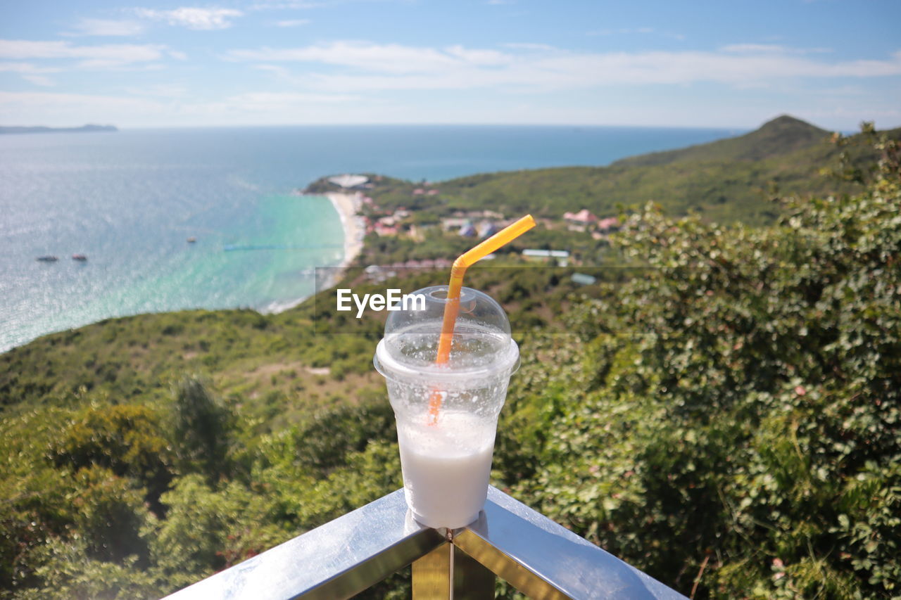 CLOSE-UP OF GLASS OF WATER AGAINST SEA