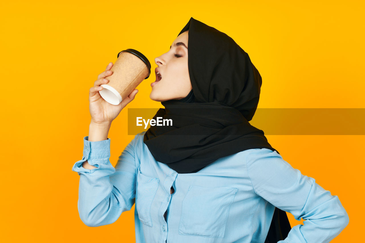 Side view of man holding food against orange background