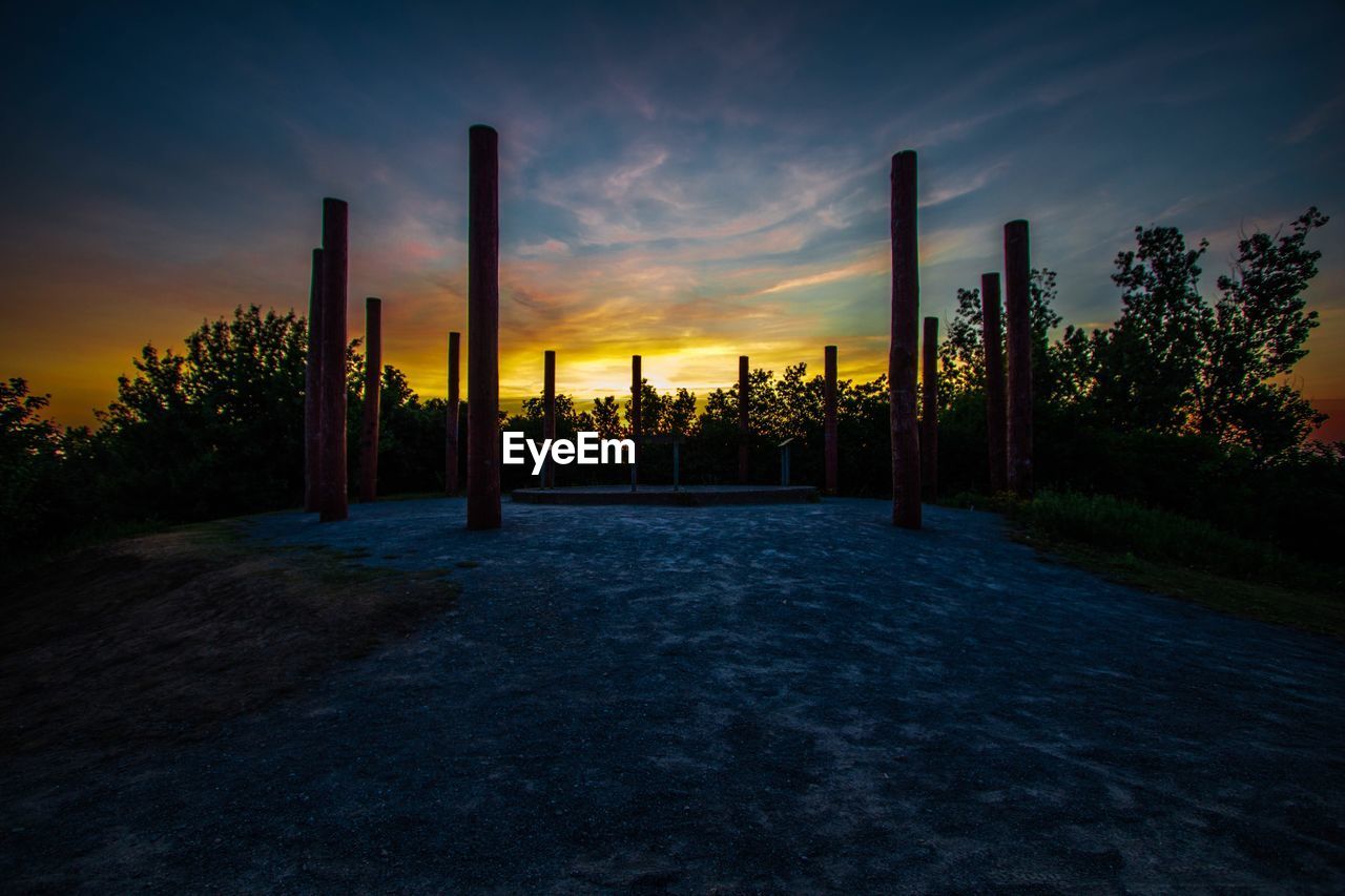 Silhouette trees on field against sky at sunset