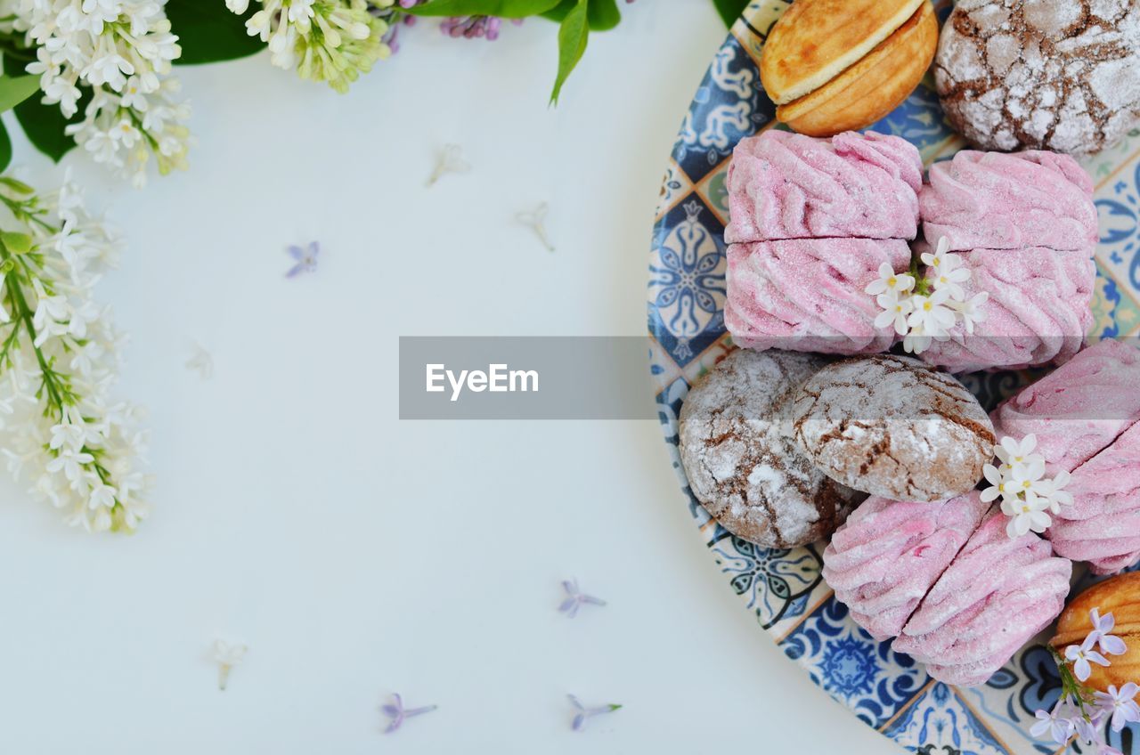 HIGH ANGLE VIEW OF PINK PETALS ON WHITE TABLE