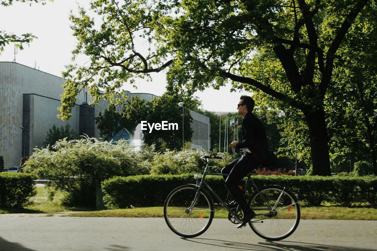 SIDE VIEW OF WOMAN WITH BICYCLE ON ROAD