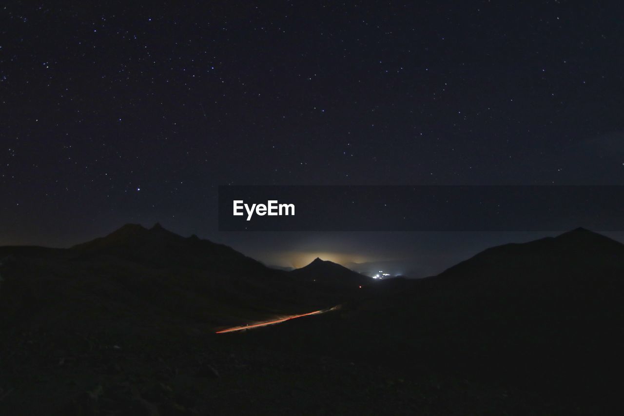 Light trail on road against mountain at night