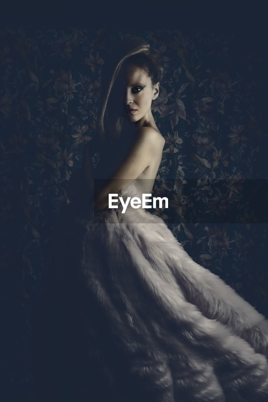 Portrait of beautiful woman standing in darkroom