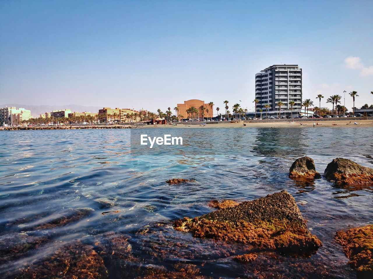 Sea by buildings against clear sky