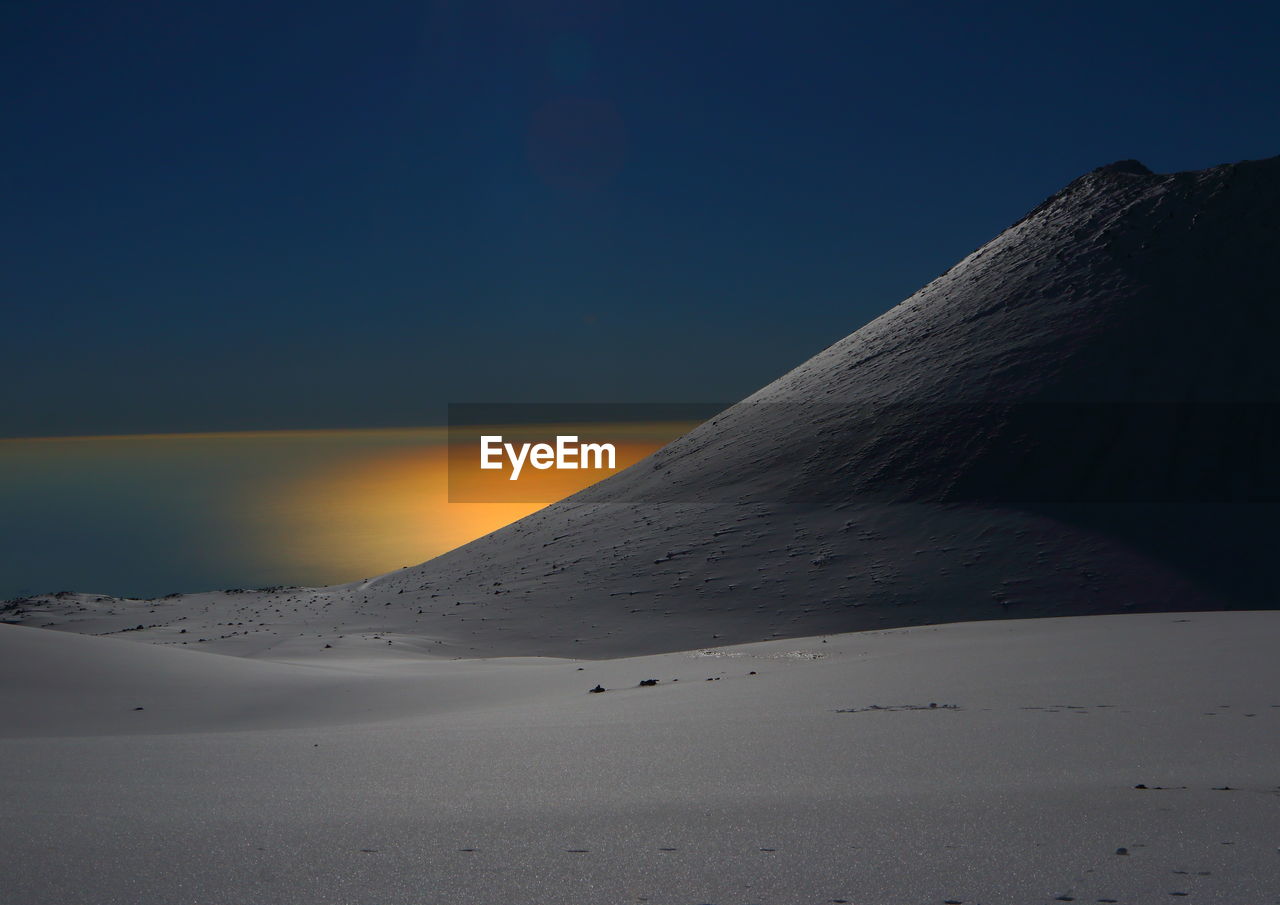 Snow covered landscape against blue sky