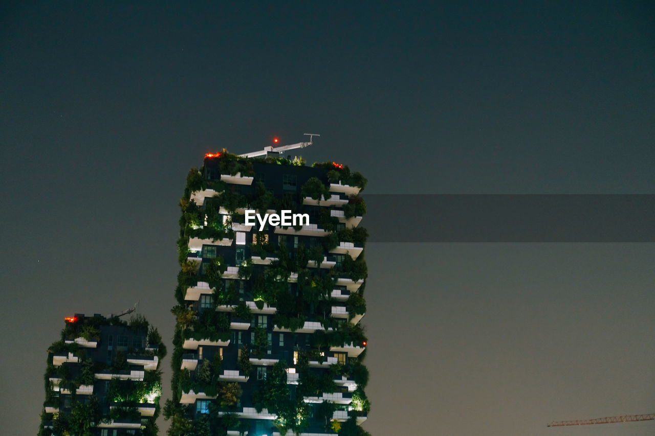 LOW ANGLE VIEW OF ILLUMINATED BUILDINGS AGAINST CLEAR SKY