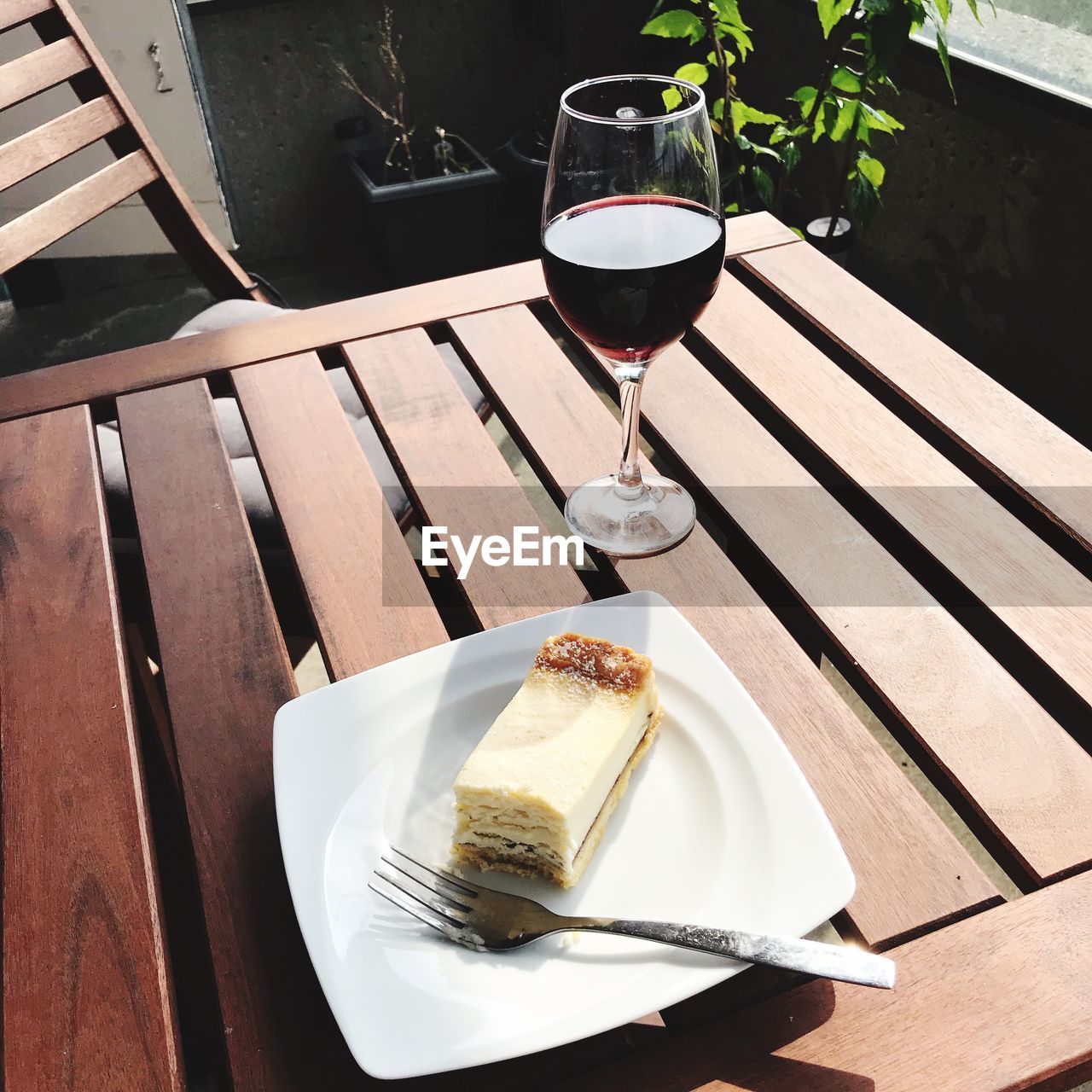 Glass of wine and piece of cheesecake on table
