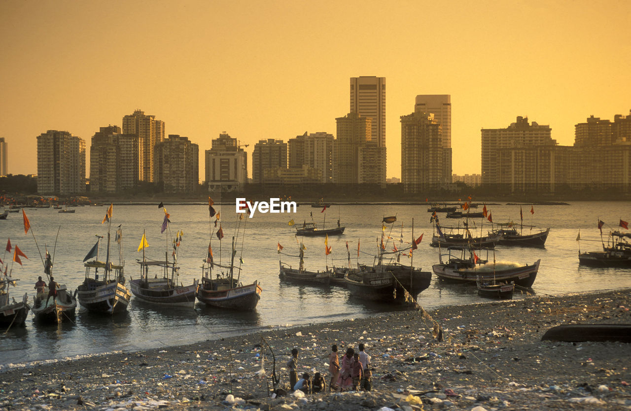 boats moored at harbor against sky during sunset