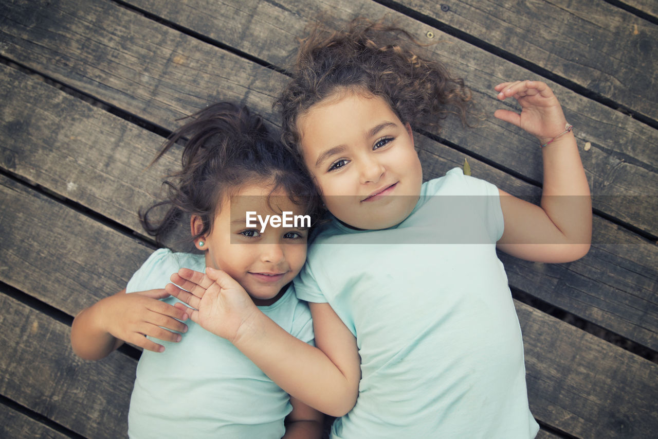 High angle portrait of siblings lying on floorboard