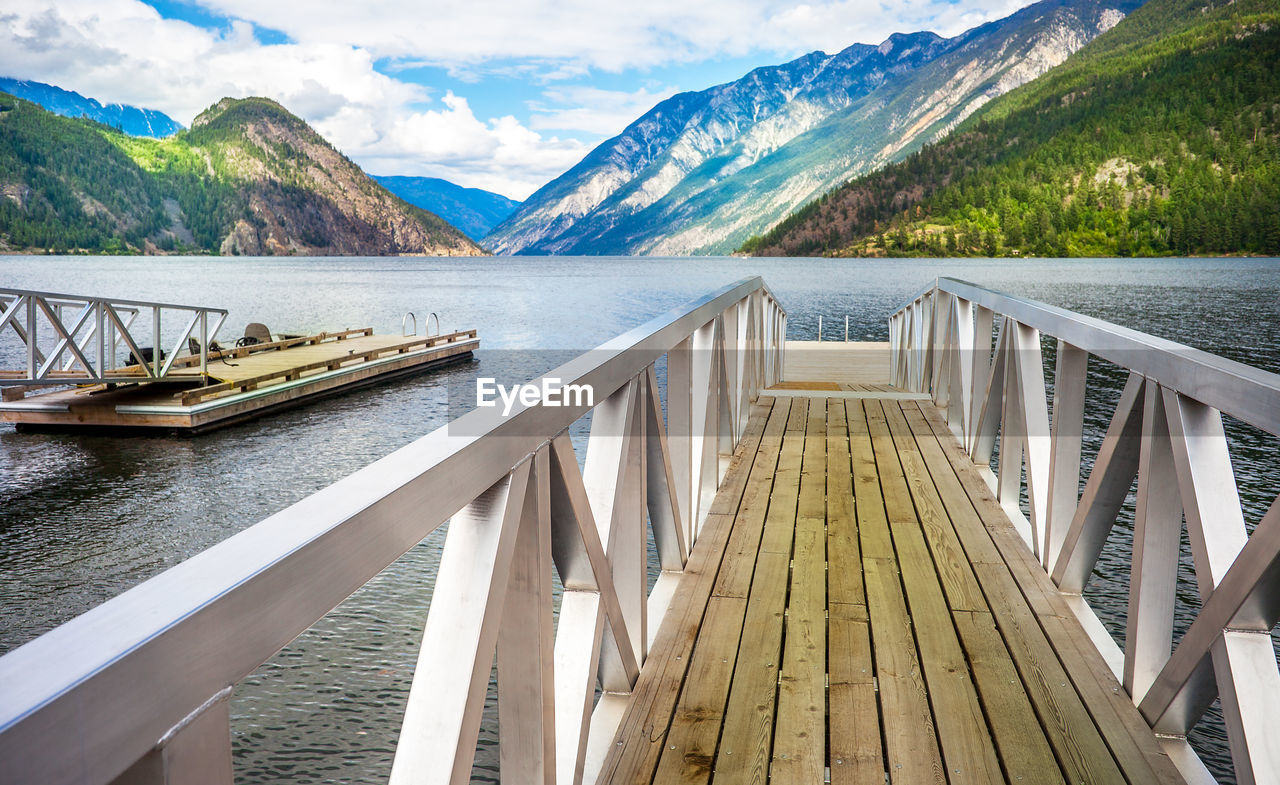 Wooden bridge over lake against sky