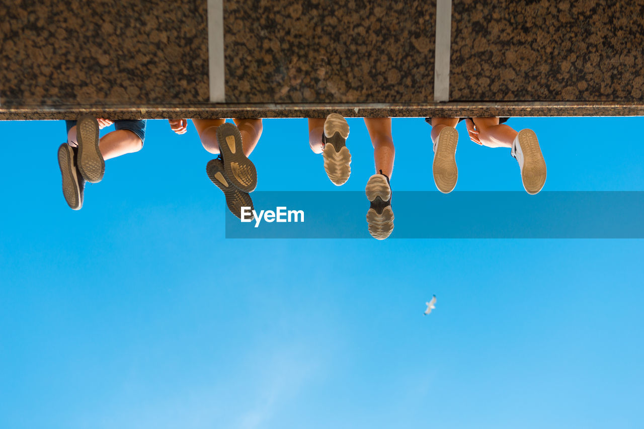 Low section of shoes hanging against blue sky